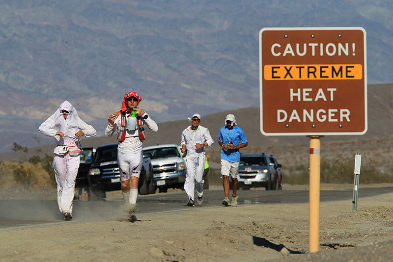 Runners pass a heat danger warning sign during the Badwater 135 ultra-marathon race in Death Valley National Park, California. (Photo by David McNew/Getty Images)
