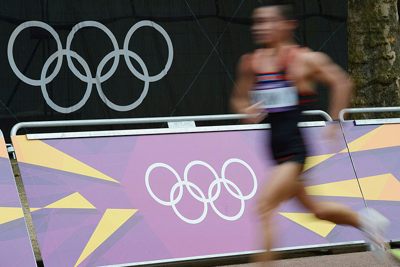 An athlete runs past Olympic rings logos while competing in the athletics event men's marathon during the London 2012 Olympic Games on August 12, 2012 in London. AFP PHOTO / ADRIAN DENNIS (Photo credit should read ADRIAN DENNIS/AFP/GettyImages)