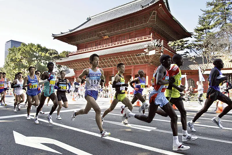 A pack of runners pass before the Zojyoji temple during the Tokyo Marathon. (Photo credit should read YOSHIKAZU TSUNO/AFP via Getty Images)